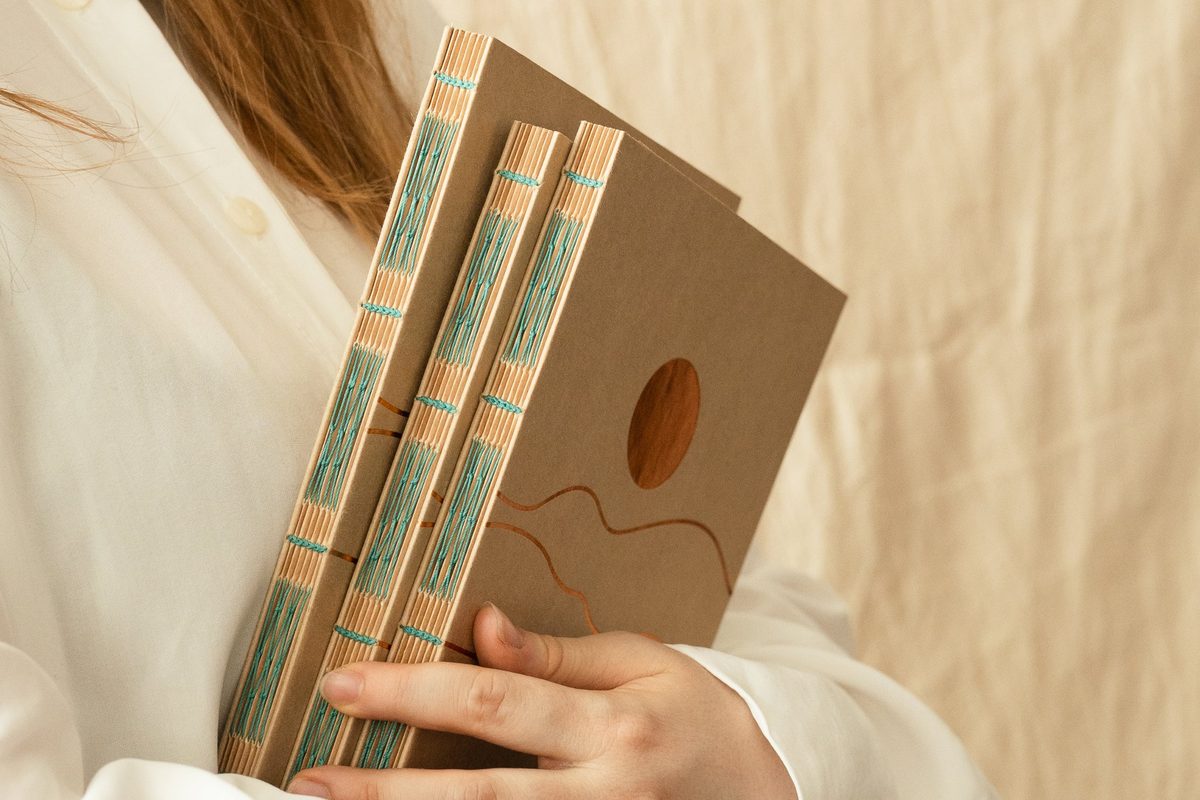 Trois carnets cousus main tenus contre soi